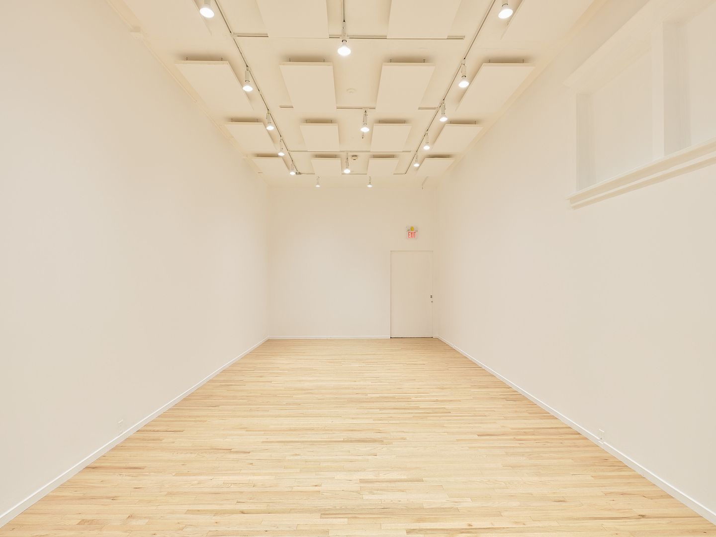 A white cube gallery space with an oak wooden floor.
