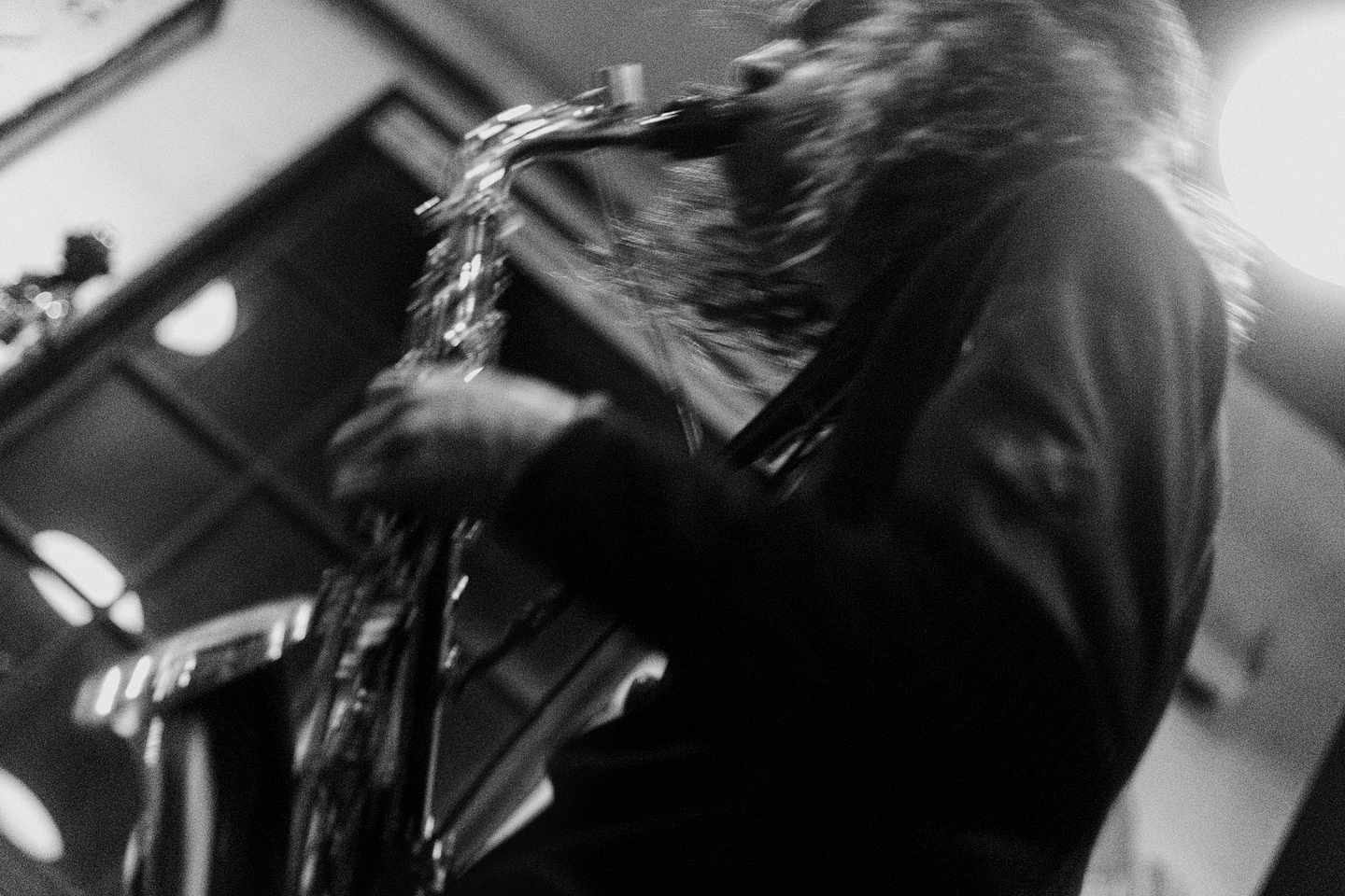 Seen from below, Jairus Sharif energetically plays saxophone, resulting in an image blur. The photo is in black-and-white. 