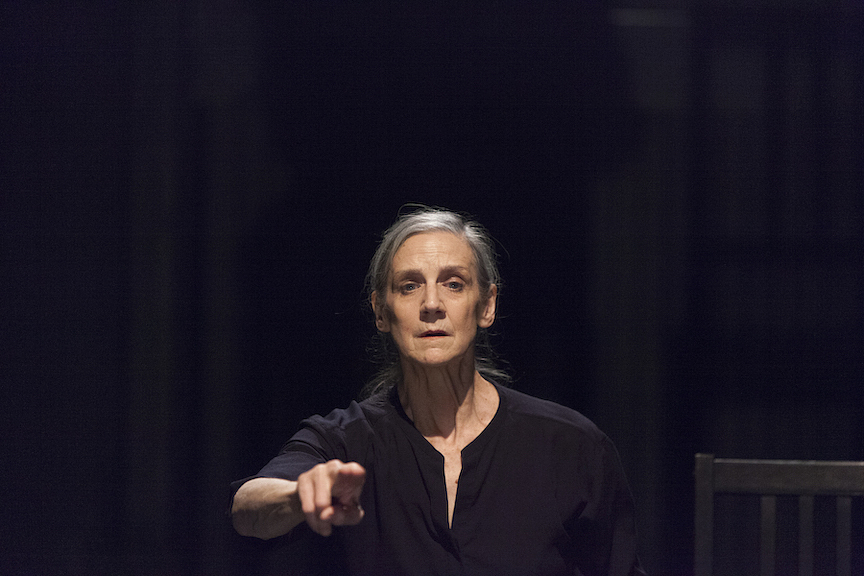 A colour photograph of Peggy Baker performing. She looks and points a finger towards the direction of the camera.