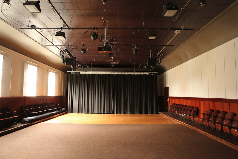 A colour photograph of Western Front’s Grand Luxe Hall. The room is empty and a black curtain hangs across the back wall.