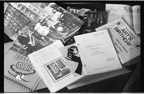 A black and white photo of a selection of printed materials from the Image Bank archives, including a poster of the Mr. Peanut Mayoral Campaign, a book titled “Fanzini Goes to the Movies,” a script titled “Mondo Artie,” and a broadsheet with the headline “Art’s Birthday."