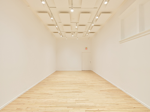 A white cube gallery space with an oak wooden floor.